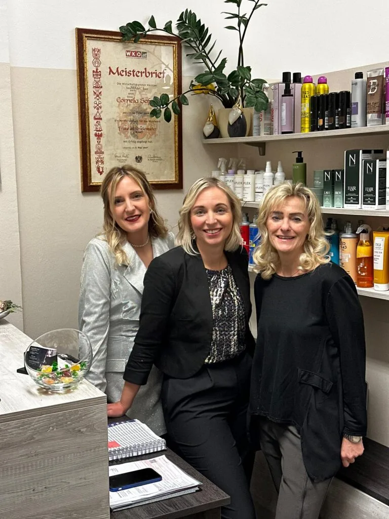 Haarstudio Style: Ihr Experte für Haarverlängerung und Styling in Klagenfurt Bild von Haarstudio Style in Klagenfurt, das die Inhaberin Frau Cornelia Buchsbaum mit zwei Mitarbeitenden zeigt. Der Salon bietet eine breite Palette an Friseurdiensten, darunter Haarverlängerungen, Extensions und Haarverdichtung. Das Studio ist bekannt für seine hochwertigen Produkte und Dienstleistungen, die in einem modernen und einladenden Ambiente durchgeführt werden. Im Hintergrund sind Regale mit diversen Haarprodukten und Styling-Tools zu sehen, die die Professionalität und Vielfalt des Angebots unterstreichen. Die Einrichtung spiegelt die Expertise und das Engagement für Qualität und Kundenzufriedenheit wider, was Haarstudio Style zu einem bevorzugten Friseursalon in Klagenfurt macht.
