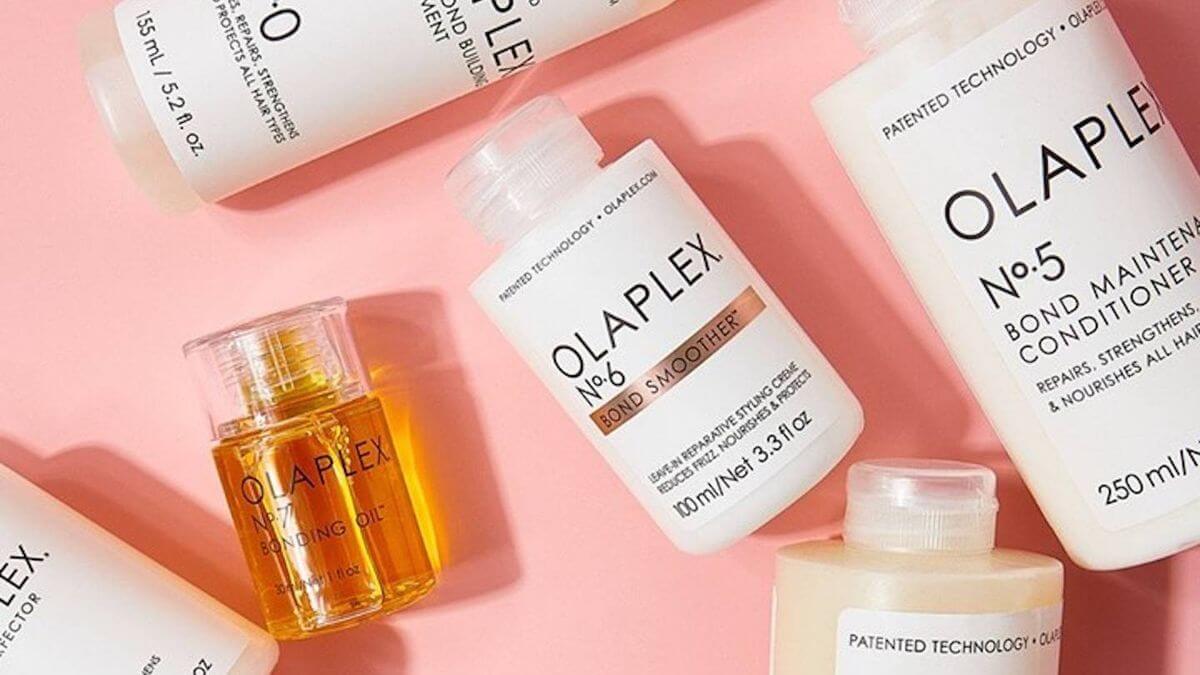 Ein Bild zeigt eine Auswahl an Olaplex Produkten, einschließlich des Bond Multiplier No.0, No.3 Haarbehandler, No.5 Bond Maintainer, No.6 Bond Smoother und No.7 Bonding Oil, auf einem rosa Hintergrund. Diese Produkte sind bekannt für ihre Fähigkeit, Haar zu reparieren, zu stärken und zu pflegen, und sind besonders beliebt in Haarstudios wie Haarstudio Style in Klagenfurt. Das Bild betont die Qualität und Vielfalt der Produkte, die im Salon verwendet werden, um den Kunden die bestmögliche Pflege zu bieten. Die Präsentation der Produkte in Flaschen und Tuben unterstreicht ihre professionelle Anwendung und die hochwertige Pflege, die im Haarstudio Style geboten wird. Die Produkte sind strategisch platziert, um ihre Wichtigkeit in der Haarbehandlung und -pflege hervorzuheben.